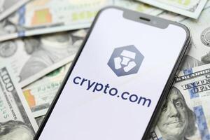 Kiev, ukraina - Mars 15, 2024 crypto com logotyp på iphone visa skärm med många hundra dollar räkningar foto