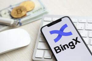 Kiev, ukraina - Mars 15, 2024 bingx logotyp på iphone visa skärm på vit tangentbord med pengar och bitcoins foto