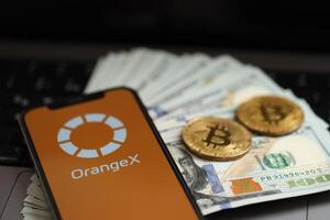Kiev, ukraina - Mars 15, 2024 orangex logotyp på iphone visa skärm med dollar och bitcoins på flap foto