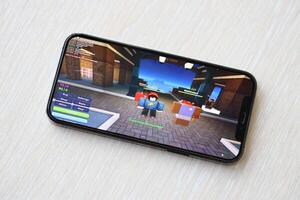 roblox mobil ios spel på iphone 15 smartphone skärm på trä- tabell under mobil gameplay foto