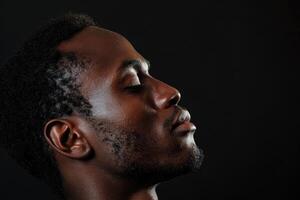 ai genererad profil porträtt lugn afrikansk amerikan man med ögon stängd och huvud tillbaka mot svart bakgrund foto