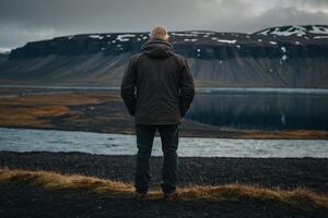 man stående på de kant av en klippa ser på de hav foto