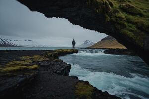 en man stående på en sten i främre av en vattenfall foto