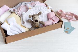 bebis och barn kläder och stickat leksaker i kartong låda. foto