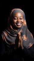 afrikansk kvinna bär scarf är bön- och leende på svart bakgrund foto