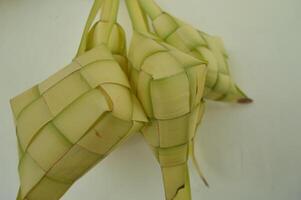 Ketupat isolerat på vit bakgrund. en typisk eid al-fitr maträtt tillverkad från ris insvept i en slå in tillverkad från vävd ung kokos löv. typisk malaysiska och indonesiska mat foto