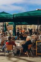 Venedig, Italien - april 2. 2023. människor är Sammanträde på de utanför terrass av en små Kafé i Venedig, Italien. foto