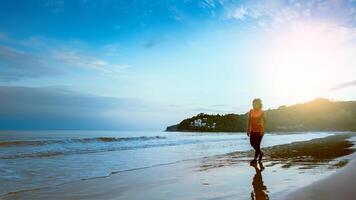 kvinna jogging träning på stranden på morgonen. koppla av med havet promenad. foto