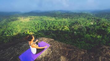 asiatiska kvinnor koppla av i semestern. spela om yoga. på bergsklippan. natur bergsskogar i thailand foto