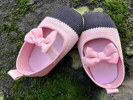 söt liten bebis skor rosa och svart Färg på plåster och mossa växter bakgrund foto