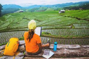 asiatisk kvinna reser naturen. resa slappna av. stående läser bok balkongen i huset. i sommar. foto