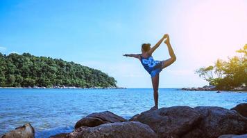 asiatisk kvinna resor koppla av i semestern. spela om yoga. på klipporna vid havet.