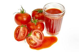 glas naturlig tomatjuice, färska röda tomater på vit bakgrund. foto