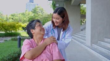 asiatisk försiktig vårdgivare eller läkare håll de patient hand och uppmuntra de patient i en rullstol. begrepp av Lycklig pensionering med vård från en vårdgivare och besparingar och senior hälsa försäkring. foto