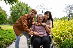 asiatisk försiktig vårdgivare eller sjuksköterska tar vård av de patient i en rullstol. begrepp av en Lycklig pensionering med vård från en vårdgivare och besparingar och senior hälsa försäkring, en Lycklig familj foto