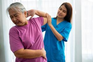 en ung asiatisk kvinnor fysioterapeut amning är bistå ett äldre kvinna övning stretching muskler på Hem eller en premie klinik för återhämtning, begrepp av fysisk terapi. foto