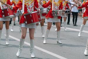 gata prestanda av festlig Mars av trummisar flickor i röd kostymer på stad gata. ung flickor handelsresande i röd årgång enhetlig på de parad foto