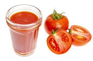 glas naturlig tomatjuice, färska röda tomater på vit bakgrund. foto