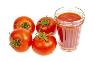 glas naturlig tomatjuice, färska röda tomater på vit bakgrund. foto