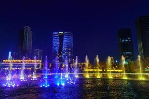 uzbekistan, Tasjkent - september 27, 2023 en fontän med laser belysning och ljus musik i Tasjkent stad parkera på natt mot de bakgrund av en scyscrapers. foto