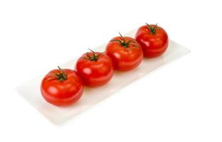fyra röda mogna tomater på vit platta. foto