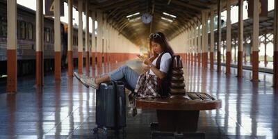 ensam resande turist använder sig av smartphone med bagage på tåg station. arbete och resa livsstil begrepp. mjuk fokus foto