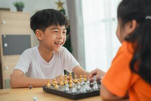 två barn spelar en spel av schack. ett är leende och de Övrig är rynkar pannan. de pojke i de vit skjorta är leende och de flicka i de orange skjorta är rynkar foto
