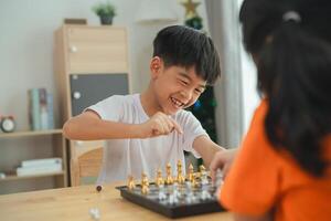 två barn spelar en spel av schack. ett är leende och de Övrig är rynkar pannan. de pojke i de vit skjorta är leende och de flicka i de orange skjorta är rynkar foto