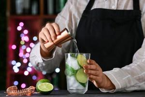 kvinnlig bartender som gör färsk mojito på bordet i baren foto