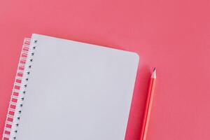 anteckningsbok med en tom sida och en penna på rosa bakgrund. foto