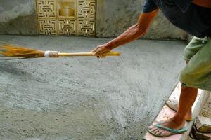 industriell fotografi. konstruktion Arbetar. Foto av en hand sotning våt cement. sopa de våt cement till skapa en grov yta textur. skott med en makro lins