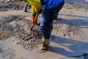 ndustrial fotografi. konstruktion arbete aktiviteter. arbetare är hakning och blandning cement med sand och stenar för cement gjutgods. bandung - Indonesien, Asien foto