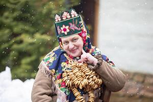 ett äldre ryska kvinna i en kokoshnik med bagels på de maslanitsa Semester. foto