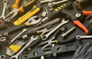 hantlangare verktyg utrustning på svart trä- tabell. många Nycklar och skruvmejslar, pålar och Övrig verktyg för några typer av reparera eller konstruktion Arbetar. reparatör verktyg foto