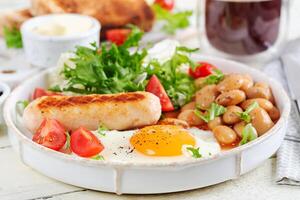 engelsk frukost. keto frukost. friterad ägg, bönor, kyckling korv och kaffe kopp. foto