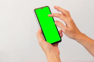 kvinnor hand innehav smart mobil telefon med tom grön skärm på isolerat vit bakgrund foto