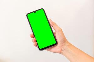 kvinnor hand innehav smart mobil telefon med tom grön skärm på isolerat vit bakgrund foto