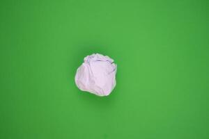 vit skrynkliga papper på en grön bakgrund. återvinning begrepp. foto