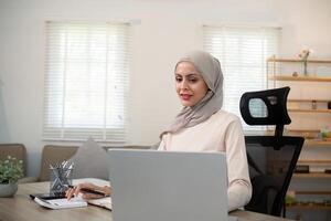 ung muslim företag kvinna revisor arbetssätt med finansiell dokumentera räkningar, Beräkna beskatta. kvinna muslim frilansare pappersarbete på Hem foto
