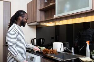 afrikansk amerikan man ung använda sig av dammtrasa rengöring i kök på Hem foto