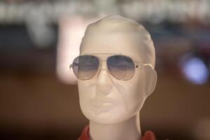 de ansikte av en manlig mannekäng i solglasögon Bakom de glas av en visa fall. foto