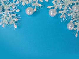 blå julbakgrund med vita snöflingor och pärlemorpärlor. kopieringsutrymme foto