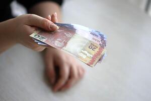 brasiliansk pengar räkningar i kvinna hand. kvinna ger knippa av brasiliansk reais till oss foto