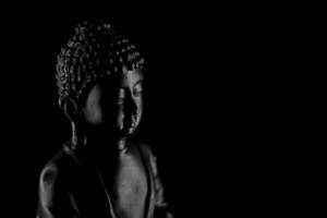 buddha purnima och Vesak dag begrepp, grå buddha staty med låg nyckel ljus mot djup svart bakgrund foto