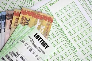 grön lotteri biljetter och brasiliansk reals pengar räkningar på tom med tal för spelar lotteri foto