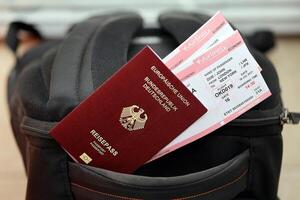 röd tysk pass av europeisk union med flygbolag biljetter på turistiska ryggsäck foto