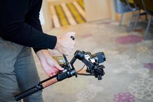 steadicam i de händer av ett erfaren kameraman, de kille skjuter bio på kamera med de hjälp av en stabilisator, Utrustning av de filma industri, skytte filmer. foto