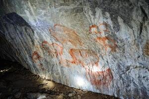 sten målningar i de grotta, gammal människor målad på de väggar av ett underjordisk bostad, bilder av en grottman, en hitta av de århundrade. foto