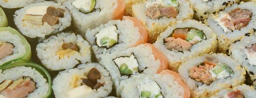 närbild av en massa av sushi rullar med annorlunda fyllningar. makro skott av kokta klassisk japansk mat. bakgrund bild foto