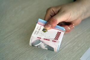 kvinna revisor hand ge knippa av många indonesiska rupiah pengar räkningar av ny serier foto